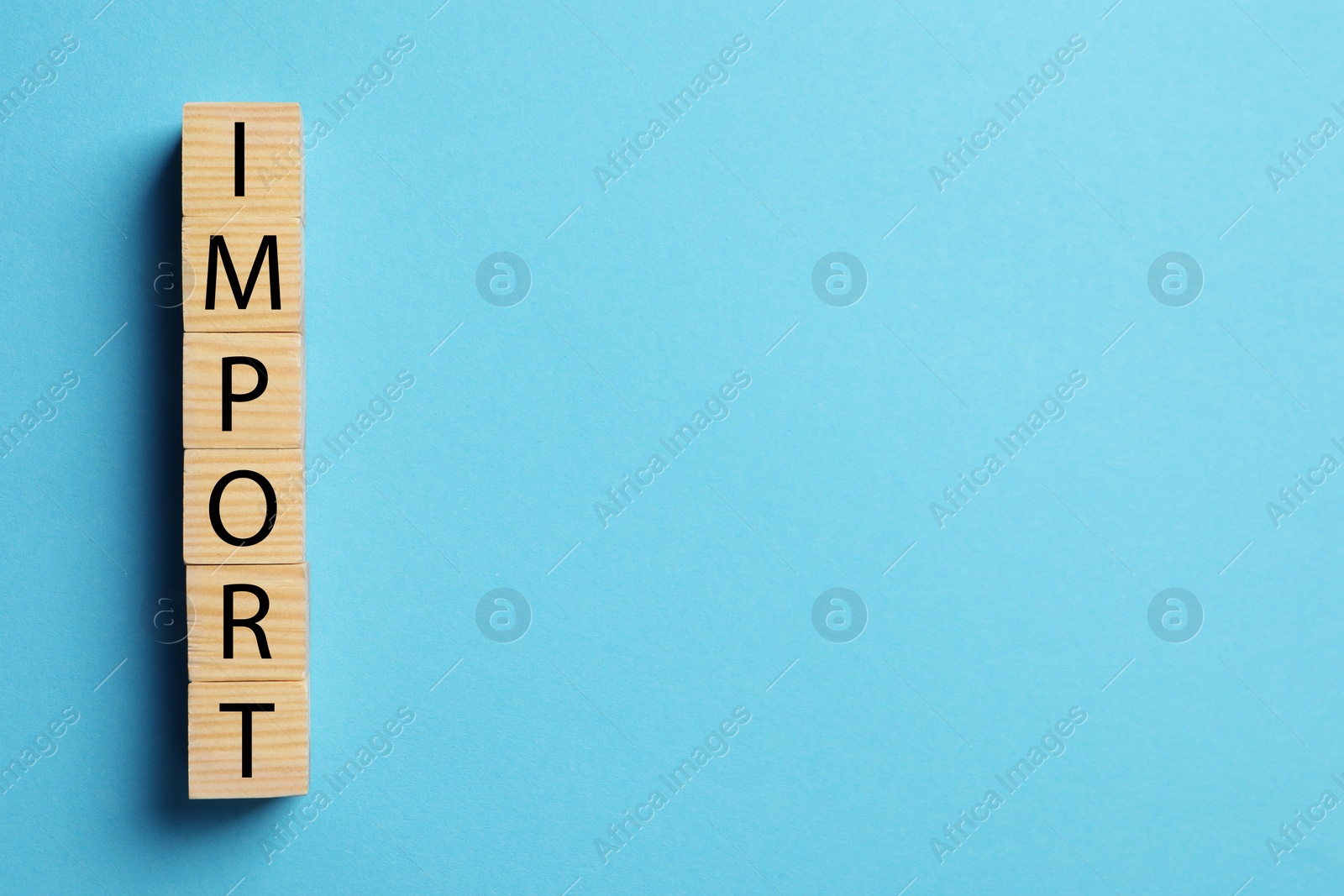 Photo of Word Import made of wooden cubes on light blue background, top view, Space for text