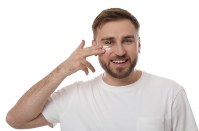 Photo of Happy young man applying facial cream on white background
