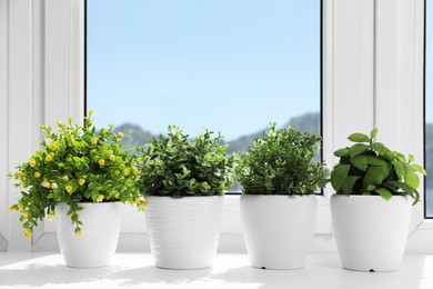 Photo of Artificial potted herbs on sunny day on windowsill indoors. Home decor