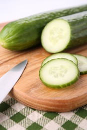 Photo of Cucumbers, knife and cutting board on table, closeup