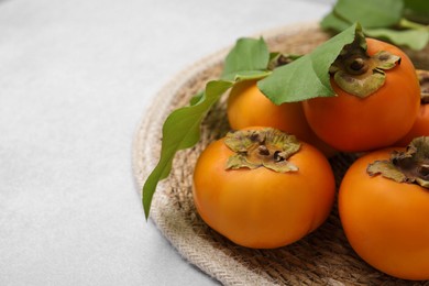 Photo of Delicious ripe juicy persimmons on white table, closeup. Space for text