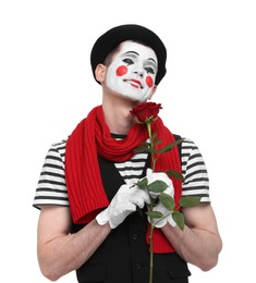 Photo of Funny mime artist with red rose on white background