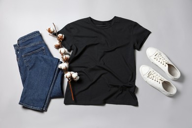 Photo of Stylish t-shirt, jeans and sneakers on light grey background, flat lay