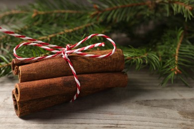 Photo of Cinnamon sticks and fir branches on wooden table, closeup