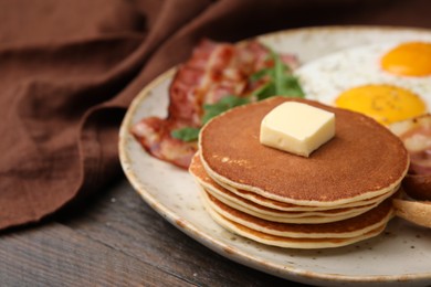 Photo of Tasty pancakes with butter on wooden table, closeup. Space for text