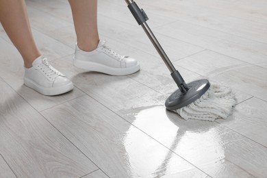Photo of Woman cleaning floor with mop indoors, closeup