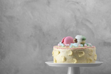 Photo of Delicious cake decorated with macarons and marshmallows against grey background, space for text