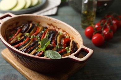 Photo of Delicious ratatouille in dish and ingredients on table