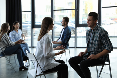 Photo of Psychotherapist working with patient in group therapy session indoors