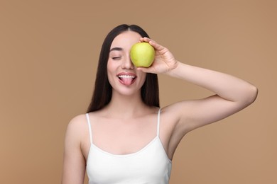 Photo of Beautiful young woman with apple on beige background