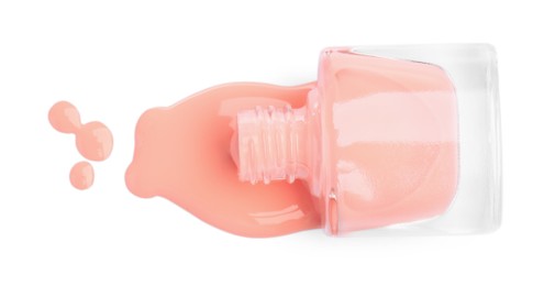 Photo of Overturned bottle of coral nail polish isolated on white, top view