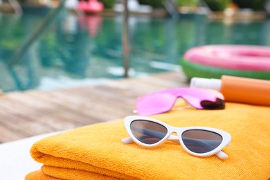 Photo of Beach towel and sunglasses on sun lounger near outdoor swimming pool at luxury resort. Space for text