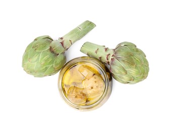 Photo of Open jar of delicious artichokes pickled in olive oil and fresh vegetables on white background, top view