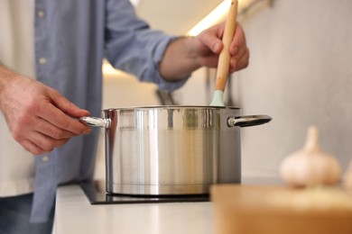 Photo of Man cooking delicious soup in kitchen, closeup