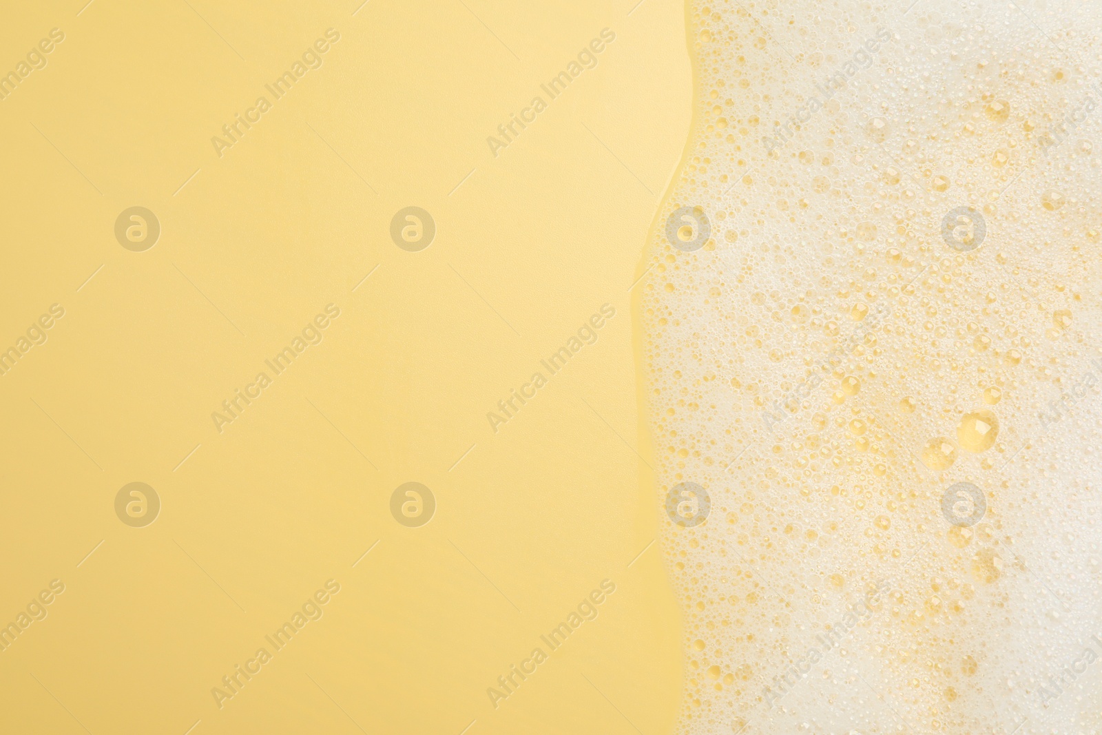 Photo of White washing foam on yellow background, top view. Space for text