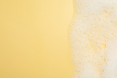Photo of White washing foam on yellow background, top view. Space for text