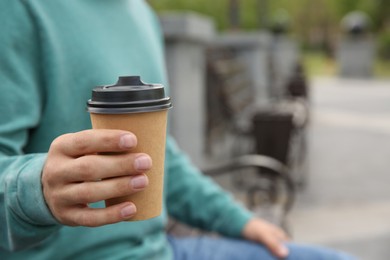 Photo of Man with takeaway coffee cup on city street, closeup. Space for text