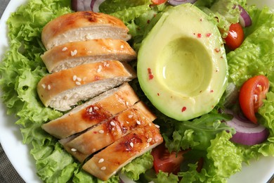 Photo of Delicious salad with chicken, avocado and vegetables in bowl, top view