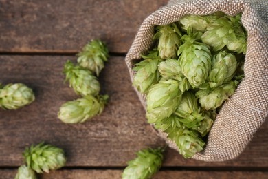 Photo of Sack and fresh green hops on wooden table, flat lay