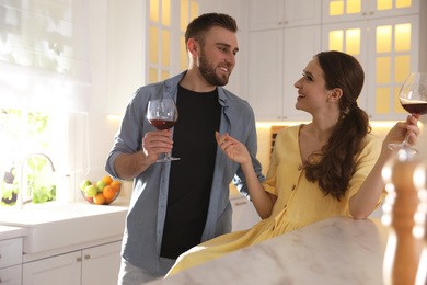 Photo of Lovely young couple drinking wine while cooking together in kitchen