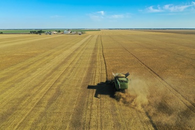 Photo of Modern combine harvester working in field on sunny day. Agriculture industry