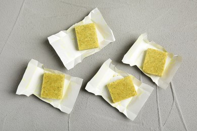 Photo of Bouillon cubes with wraps on light grey table, flat lay