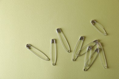 Photo of Safety pins on green background, flat lay. Space for text