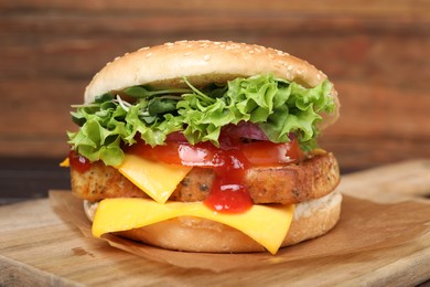 Photo of Delicious burger with tofu, fresh vegetables and sauce on wooden board, closeup