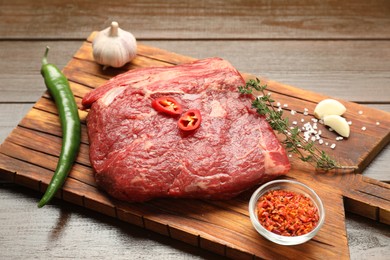 Photo of Fresh raw beef cut with spices on wooden table