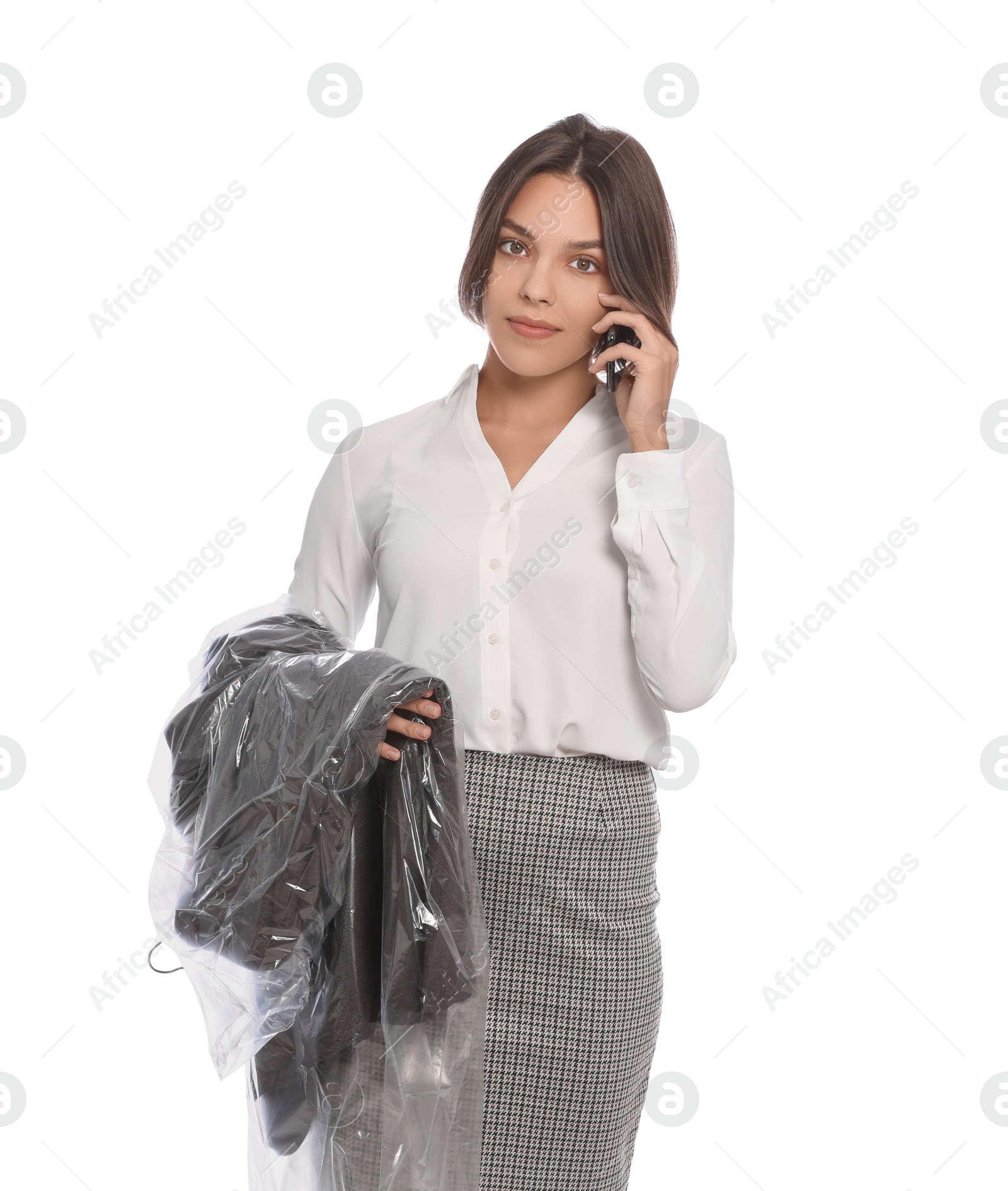 Photo of Woman holding garment cover with clothes while talking on phone, isolated on white. Dry-cleaning service