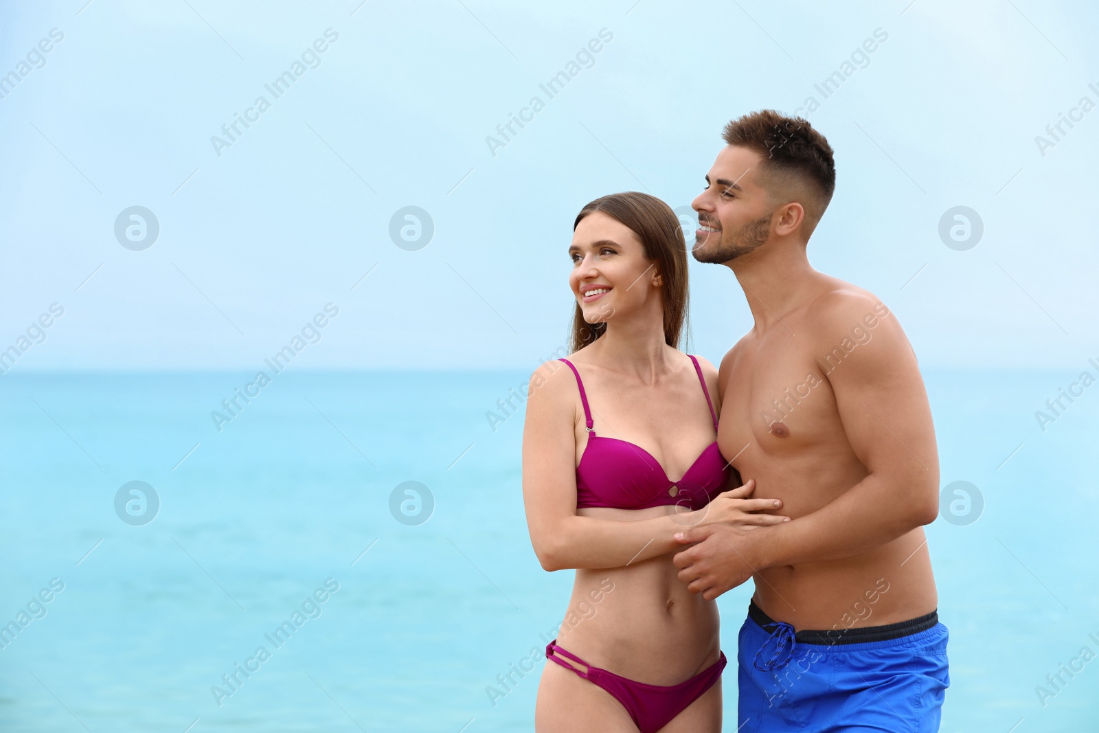 Photo of Young woman in bikini with her boyfriend on beach, space for text. Lovely couple