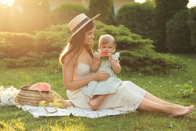 Photo of Mother with her baby daughter having picnic in garden on sunny day