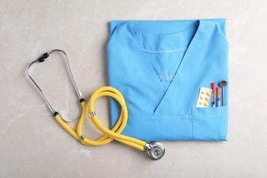 Photo of Top view of stethoscope and medical uniform on light background