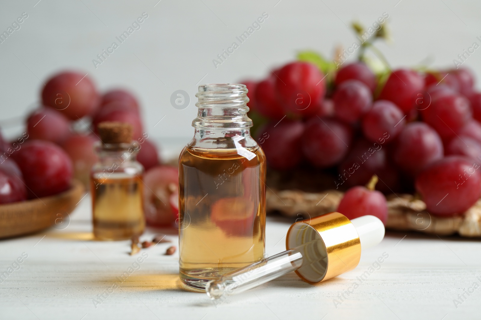 Photo of Bottle of natural grape seed oil on white wooden table. Organic cosmetic