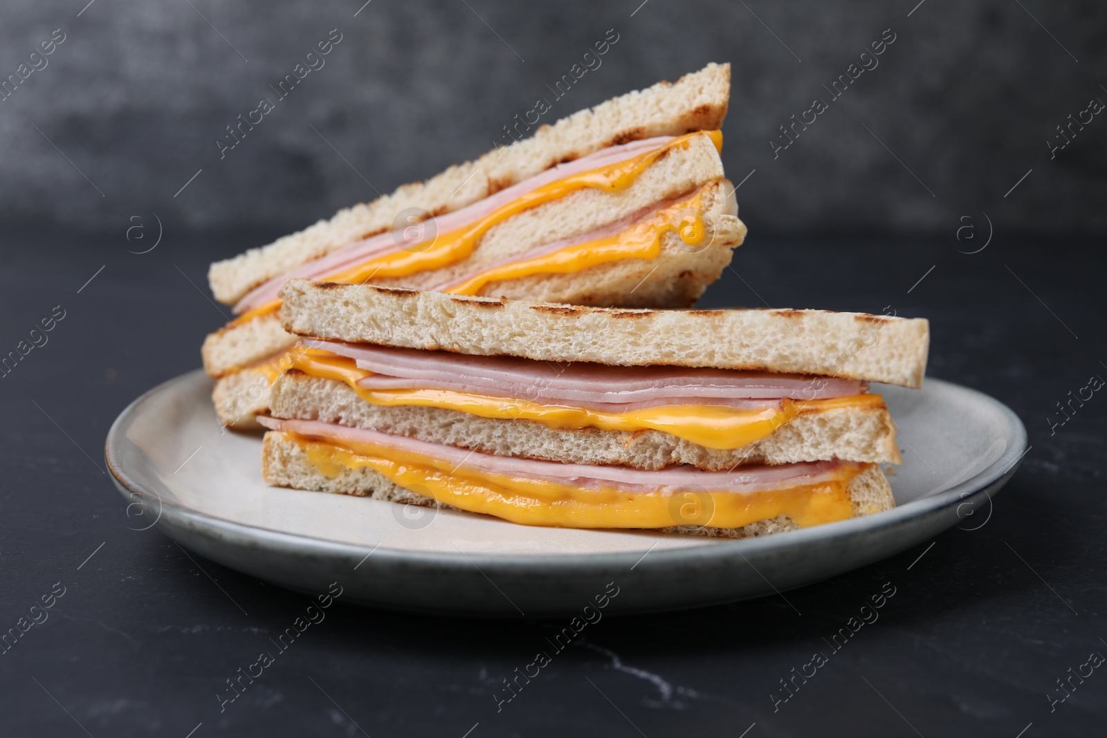 Delicious grilled sandwiches with ham and cheese on black table, closeup Photo of Delicious grilled sandwiches with ham and cheese on black table, closeup