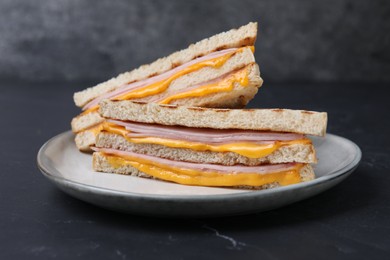 Photo of Delicious grilled sandwiches with ham and cheese on black table, closeup