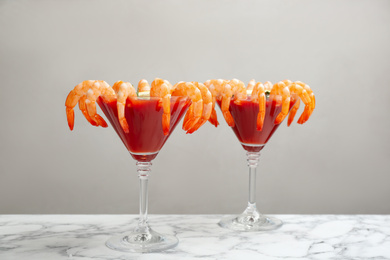 Photo of Shrimp cocktail with tomato sauce on marble table