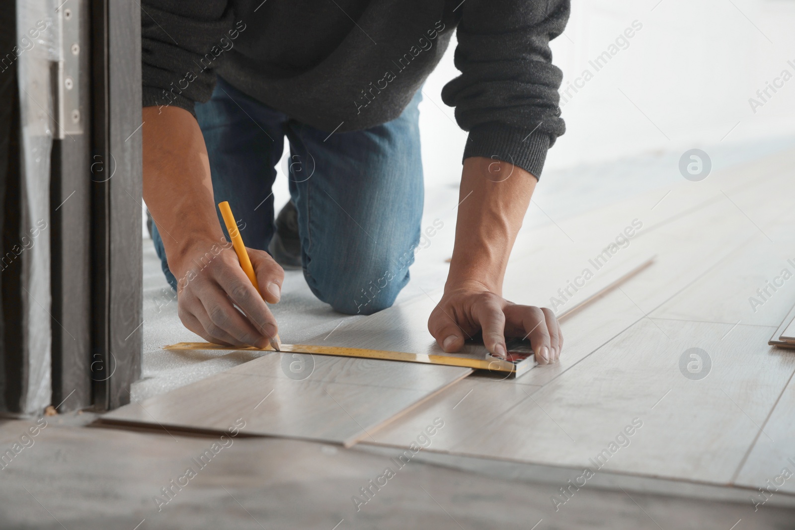 Photo of Worker installing new laminate flooring in room, closeup