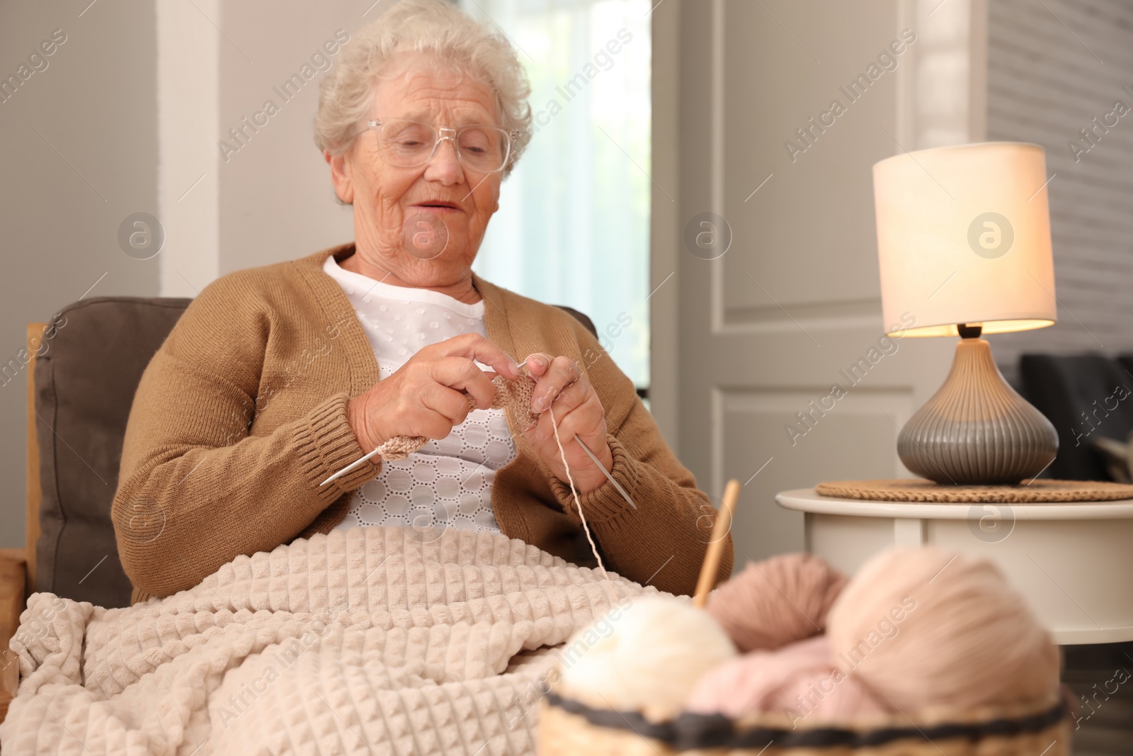 Photo of Elderly woman knitting at home. Creative hobby