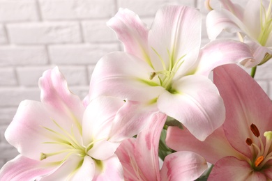 Photo of Beautiful blooming lily flowers on brick wall background