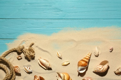 Photo of Flat lay composition with seashells, beach sand and space for text on wooden background