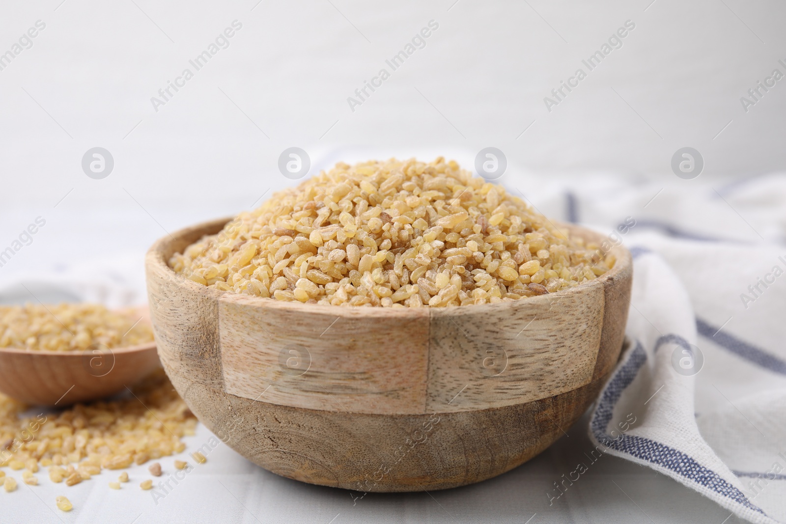 Photo of Raw bulgur in bowl on table, closeup