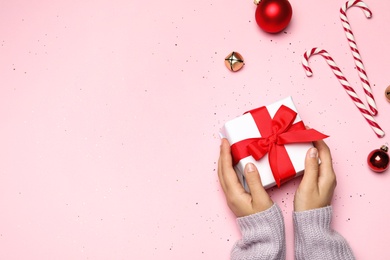 Young woman holding Christmas gift on pink background, flat lay. Space for text