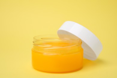 Open jar of petrolatum on yellow background