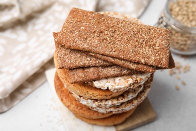 Photo of Stack of rye crispbreads, rice cakes and rusks on white table, closeup
