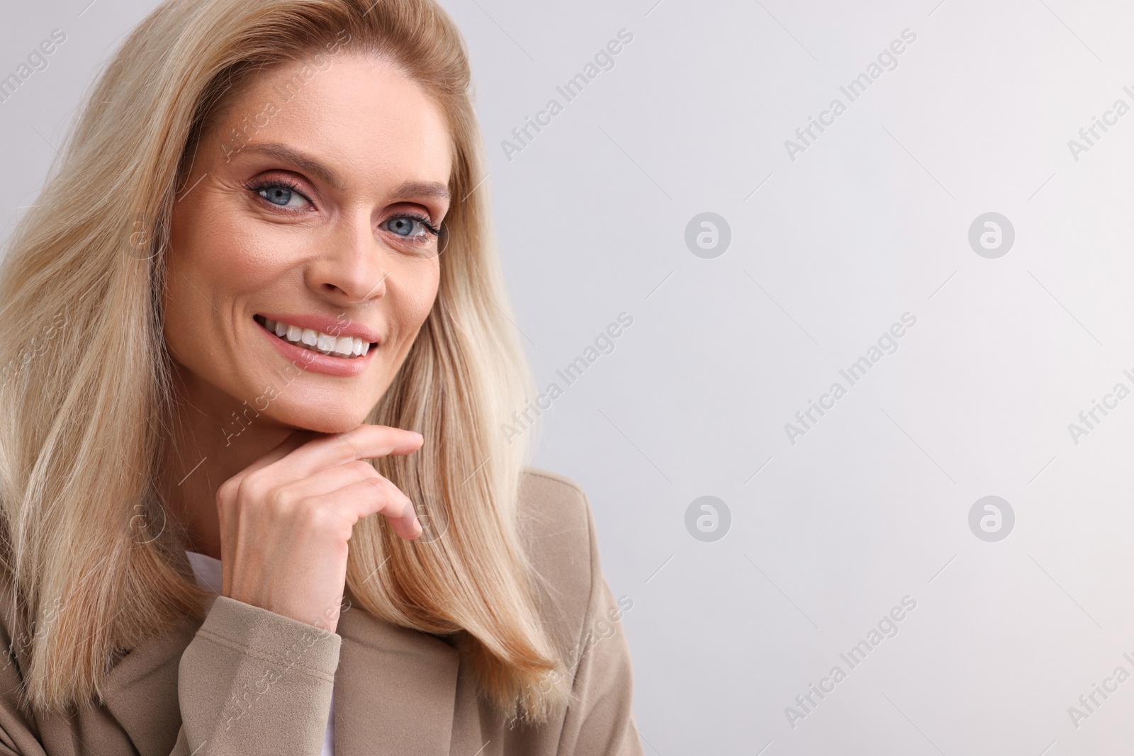 Photo of Portrait of smiling middle aged businesswoman on light grey background. Space for text