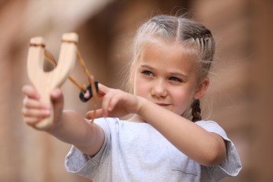 Photo of Little girl playing with slingshot on city street
