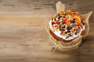 Photo of Traditional Easter cake with dried fruits on wooden table, space for text