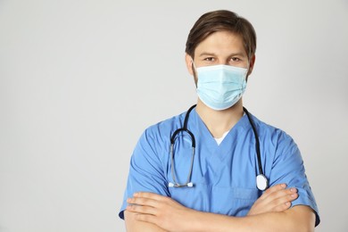 Photo of Doctor or medical assistant (male nurse) with protective mask and stethoscope on light grey background. Space for text