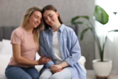 Photo of Blurred view of happy young women sitting on bed at home, space for text
